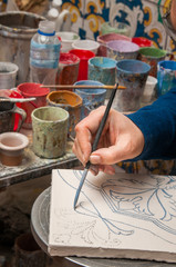 Pottery artisan in Caltagirone, Sicily, decorating just enamelled square tiles in his work table