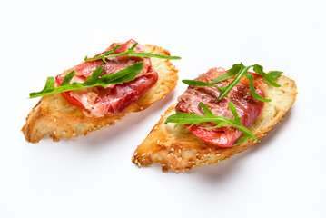 Two bruschettes with serrano ham, cheese and arugula