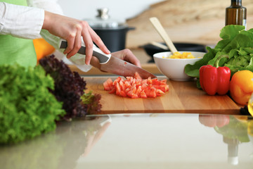 Closeup of human hands cooking vegetables salad in kitchen on the glassr table with reflection. Healthy meal and vegetarian concept