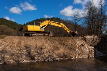 Excavator on the work to strengthen the shoreline of the river.