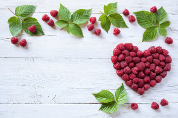 Berries raspberries in a heart shape on wooden background