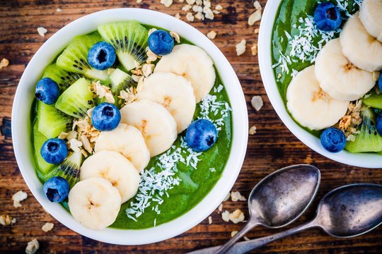 Green smoothie bowl with banana, kiwi, blueberry, granola and coconut