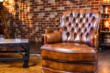 Leather armchair against stone wall. Vintage armchair in loft.