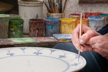 Fototapeta na wymiar Pottery artist in Caltagirone, Sicily, decorating a ceramic dish in his workshop