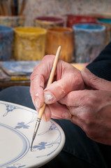 Fototapeta na wymiar Pottery artist in Caltagirone, Sicily, decorating a ceramic dish in his workshop