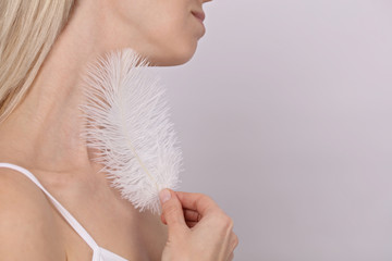 Attractive young woman touching her smooth perfect skin after beauty treatment with feather.