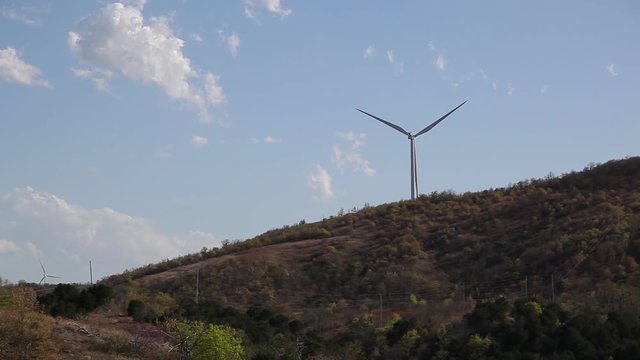 Power generating windmill spinning on a forested hill