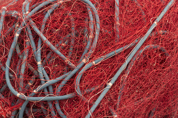 Mess of red fishing net and grey ropes 