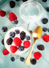 Jar of yogurt with blueberries, blackberries and raspberries.