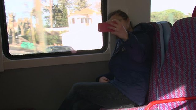 Student girl taking selfie photo on smartphone sitting on train or bus 