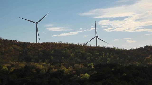 Double Wind Turbines on hill with trees