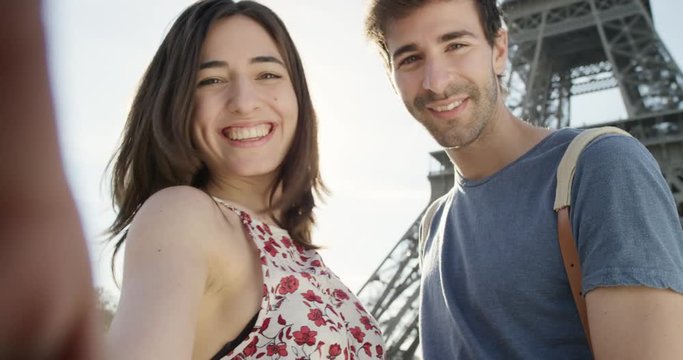 Tourist couple taking  photograph selfie under Eiffel Tower Paris smartphone in city sharing lifestyle photo enjoying  holiday European   vacation travel adventure POV