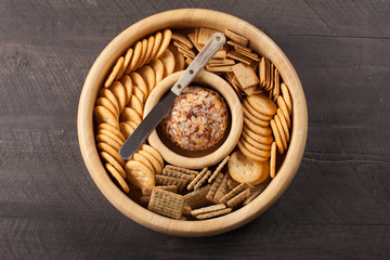 Cheese ball with various crackers in wooden container on dark wooden background horizontal shot