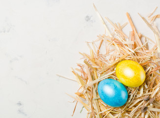 Easter background with multi-colored chicken eggs on a white stone slab.