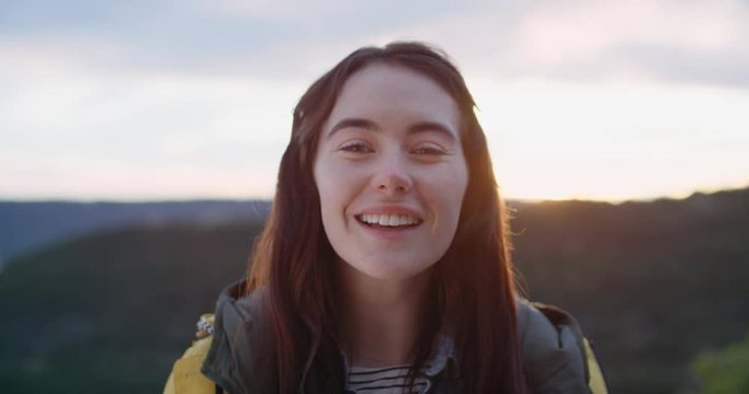 Close up portrait of beautiful young brunette woman laughing smiling at sunset outdoors natural light shining through healthy hair blowing in wind slow motion