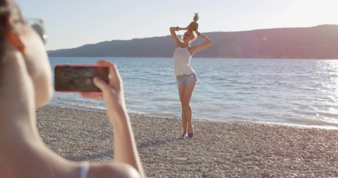 Close up attractive woman balancing pineapple on head posing for camera smiling laughing at sunset on tropical beach