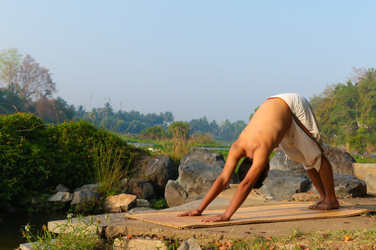 An Indian yogi performing yoga asanas on a riverbank in India.