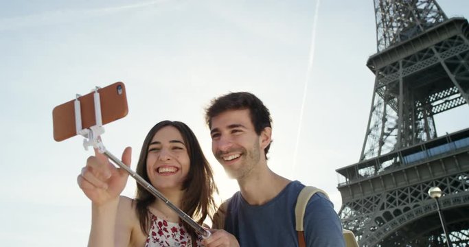 Tourist couple taking selfie under Eiffel Tower Paris smartphone in city sharing lifestyle photo enjoying  holiday European   vacation travel adventure 