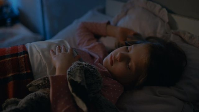 Sweet Little Girl Sleeps in Her Bed while Hugging Her Plush Toys. Shot on RED EPIC-W 8K Helium Cinema Camera.
