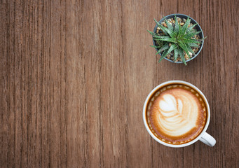 Coffee cup with plant top view on old wooden