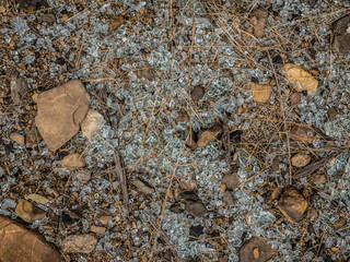Smashed glass spread over the ground between rocks