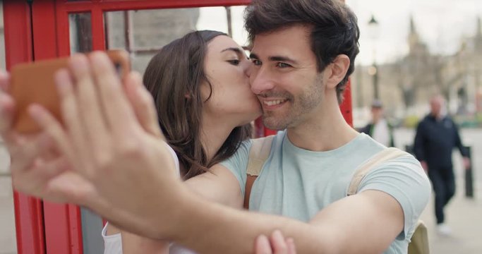 Tourist couple taking selfie in Red Phone Booth smartphone in city sharing lifestyle photo enjoying  holiday European   vacation travel adventure London