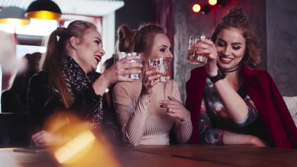 Close up view of three girls friends chatting, laughing, cheering up and drinking alcohol cocktails in the club. Having fun, being happy. True friends. Entertaining atmosphere.