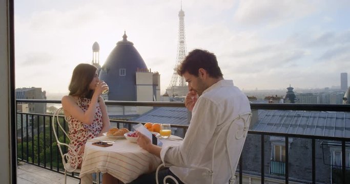 Young tourist couple in Paris hotel enjoying breakfast on terrace view of Eiffel Tower at Sunrise in the morning