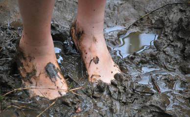 Kid's muddy feet. Selective focus.