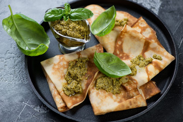 Close-up of freshly baked crepes with basil pesto sauce, studio shot