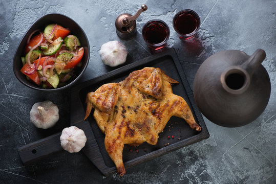 Roasted chicken tabaka served with red wine and vegetable salad, view from above