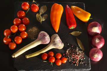 Vegetables and spices before cooking dinner on a dark background, top view
