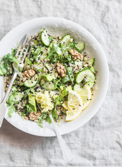 Green vegetables quinoa salad for a spring detox. Salad with quinoa, avocado, cucumbers, arugula, walnuts, ginger and seeds. On a gray background, top view. Healthy vegetarian food concept