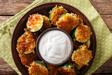 Fried zucchini slices in breaded Panko with sour cream close-up. Horizontal top view