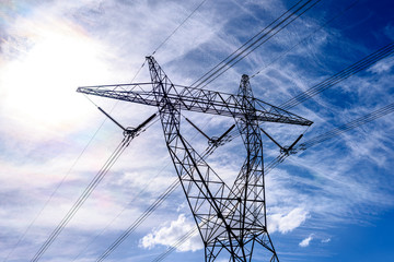 High voltage power transmission tower on blue sky background,  electricity distribution.