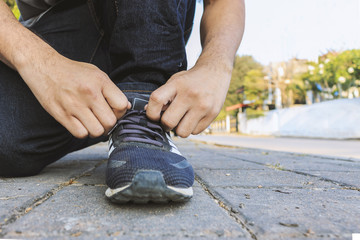 A man tie his sneaker shoes with soft-focus in the background. over light and film colors tone