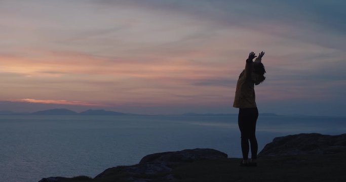 Woman with arms raised on top of mountain looking at Sunset view over ocean Hiker Girl celebrating scenic landscape enjoying nature vacation travel adventure Isle of Skye Scotland