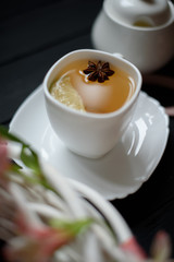 Hot tea with cardamom and lime over rustic black wooden background	