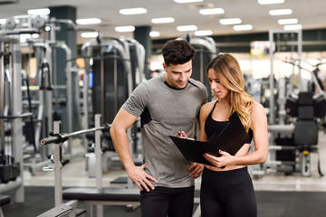 Personal trainer and client looking at his progress at the gym