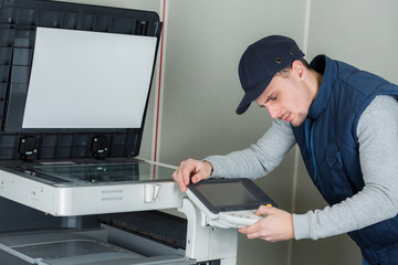 young male technician repairing digital photocopier printer machine