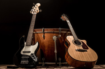 Obraz na płótnie Canvas musical instruments, bass drum barrel acoustic guitar and bass guitar on a black background