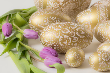 golden eastern eggs on white with purple tulip