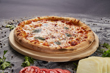 Italian delicious fresh pizza with tomato and pepperoni on a dark background.  Pizza on the black table. with ingredients