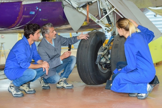 engineer and apprentices checking airplane wheels