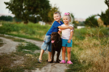 Fototapeta premium Two children walking with a dog breed Labrador