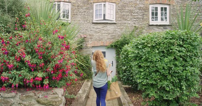 Redhead British Woman Arriving Home With Flowers And Groceries At Country Cottage In Cornwall, England