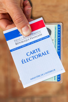 carte électorale française et carte d'identité tenues en main pour voter