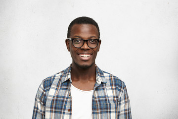 Close up of attractive smart-looking smiling dark-skinned male model posing for social advertisement, isolated on white background with blank copy space for your promotional information or content