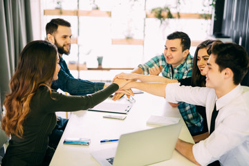 Team put hands together, show connection and alliance, top view of working table. Teambuilding in office, young businessmen and women in casual unite hands for teamwork and cooperation at new project.