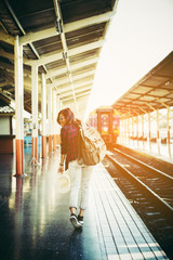 Young hipster woman waiting on the station platform with backpack. Travel concept.